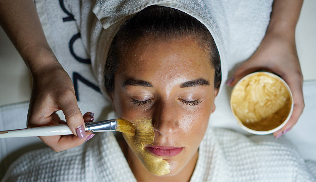Woman at spa having face mask applied