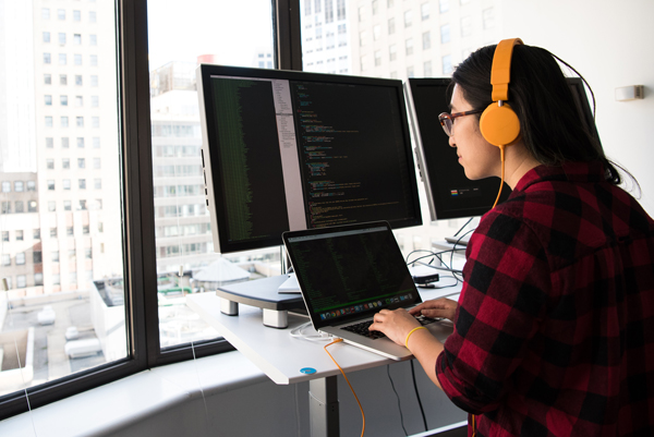 Woman developing software on multiple screens