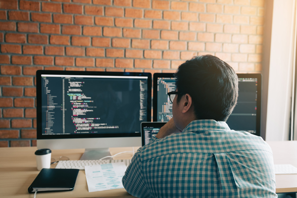 Man developing website on two computer screens